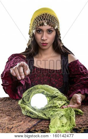 Female psychic or fortune teller pointing finger forward at the viewer. She has a crystal ball and isolated on a white background