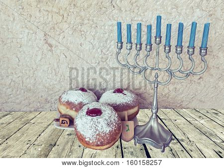 Jewish menorah with candles and sweet donuts are traditional symbols for Hanukkah holiday