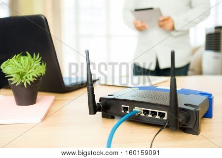 closeup of a wireless router and a man using Tablet on living room at home ofiice