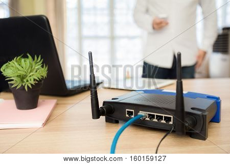 closeup of a wireless router and a man using smartphone on living room at home ofiice