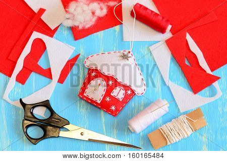 Christmas tree house decoration sewn from felt and decorated with snowflakes and metal parts. Tools and materials to create Christmas tree decoration. Handmade Christmas DIY concept. Closeup. Top view