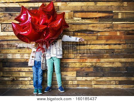 Children with red balloons at wooden wall