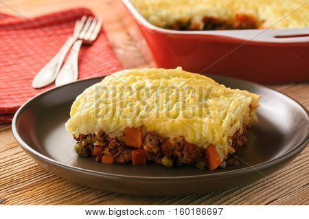 Shepherd pie (portion) on plate on wooden table.