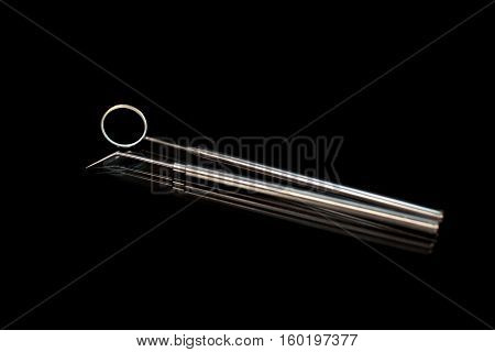 Dental mirror and dental sonde. Image isolated on black background.