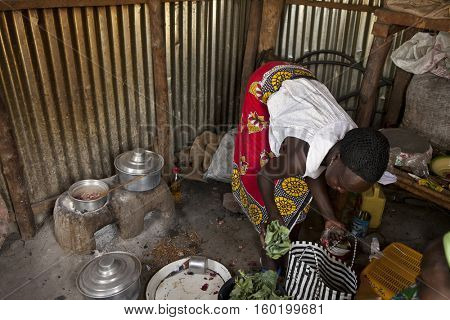BOR, SOUTH SUDAN, FEBRUARY 26, 2013: A woman cooks using traditional methods over a small charcoal oven in South Sudan. Charcoal is the only method of cooking in this region.