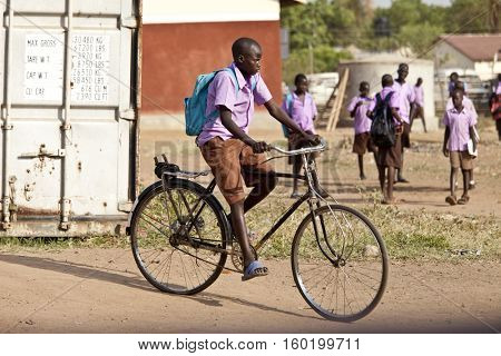 TORIT, SOUTH SUDAN-FEBRUARY 20, 2013: Unidentified student rides his bicycle from school in the village of Torit, South Sudan
