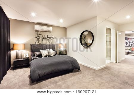 Modern bedroom with a round mirror and hallway through the luxury house