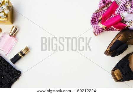 Flat lay. Ladies accessories. Night clutch purse lip stick women perfume high heel shoes and fashion scarf on white background. Christmasgift for her concept. Copy space