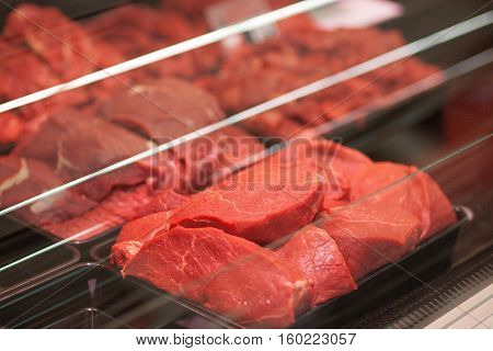 Different types of raw meat in plastic boxes in supermarket
