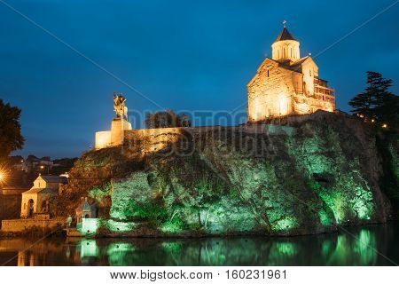 Night Evening Illuminated View Of The Metekhi Church And The Equestrian Statue Of King Vakhtang Gorgasali On The Metekhi Cliff In Old Historic District Of Tbilisi Georgia. Blue Hour. Blue Evening Sky.