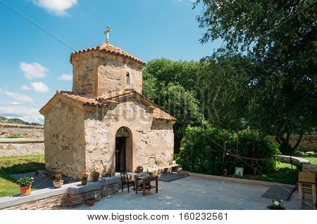 Mtskheta, Georgia. The View Of Ancient Tiny Stone Church Of St. Nina With Green Churchyard At Samtavro Monastery Complex Area In Sunny Day Under Blue Sky.