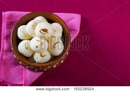 Indian Sweet - Rasgulla, Famous Bengali sweet in clay bowl with napkin on pink background