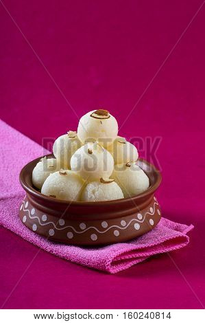 Indian Sweet - Rasgulla, Famous Bengali sweet in clay bowl with napkin on pink background