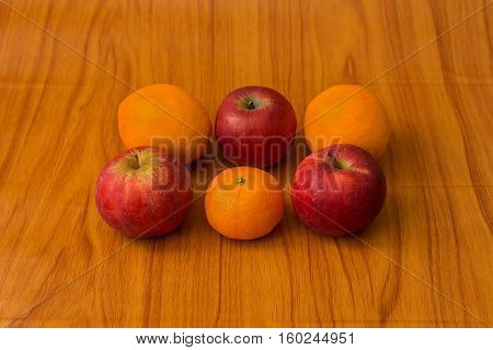 Raw Apples and Oranges on brown background