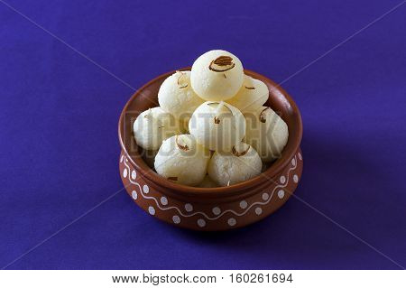 Indian Sweet or Dessert - Rasgulla, Famous Bengali sweet in clay bowl on blue background