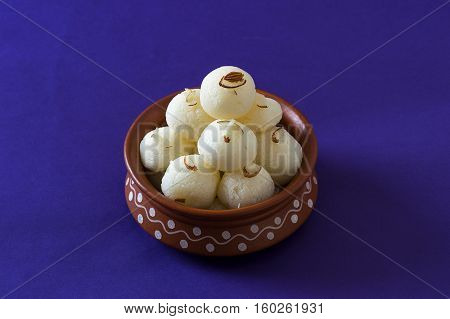 Indian Sweet or Dessert - Rasgulla, Famous Bengali sweet in clay bowl on blue background
