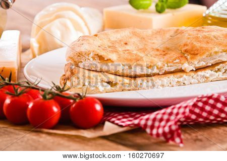 Cheese focaccia bread and other ingrediets on white dish.