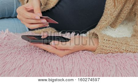 Young woman buying goods from the internet and entering number security code from credit card on smartphone. Online, technology and internet concept.