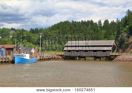 Built in 1935 still in use Covered Wooden Bridge Irish River #1 or Vaughan Creek Bridge St. Martins area New Brunswick part of marina for commercial lobster fishing in moment of high tide