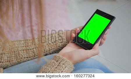 Woman looking at smartphone with green screen. Close up shot of woman's hands with mobile