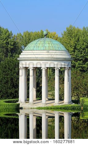Water reflection of an ancient temple with the dome and the white stone column
