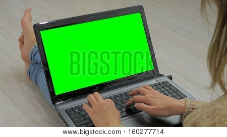 Woman using laptop with green screen. Woman's hands typing on a laptop keyboard. Business, communication, freelance and internet concept