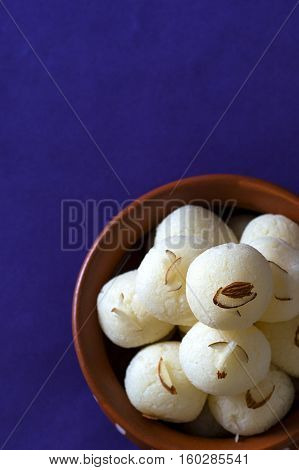 Indian Sweet or Dessert - Rasgulla, Famous Bengali sweet in clay bowl on blue background