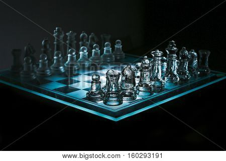Close up view of a corner of glass transparent chess board with chess pieces on black background