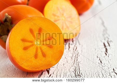Japanese persimmon (Diospyros kaki) on white rustic wooden background. Copy space