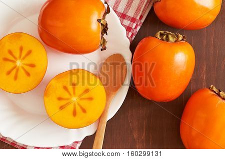 Japanese persimmon (Diospyros kaki) served on white plate. Top view