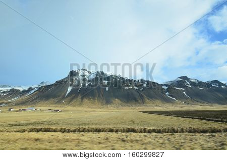 Farm buildings located at the base of the Rhyolite Mountains in Iceland.