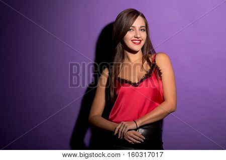 Happy smiling beautiful model woman with long brown hair posing in studio. Lady with red lips smiling and looking at camera with her hands clasped.