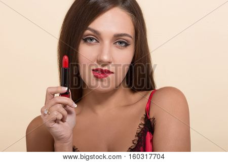 Young model woman showing red colored lipstick for doing makeup isolated on white. Pretty lady with red lips looking at camera.