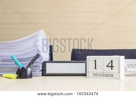 Closeup white wooden calendar with black 14 december word on blurred brown wood desk and wood wall textured background in office room view with copy space selective focus at the calendar