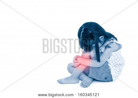 Sadness asian child barefoot sitting on floor with copy space. Girl hurt at shin isolated on white background. Photo with color increase blue skin and red spot indicating location of pain.