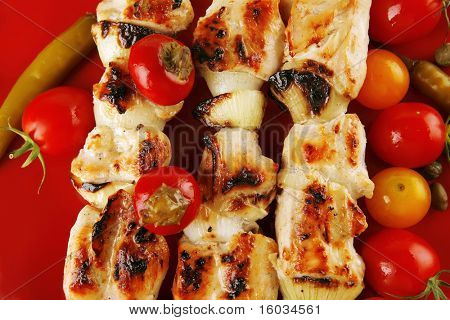 Chicken shish kebab på røde fad med grøntsager