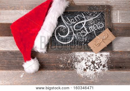 Christmas decoration with place for greeting on chalk blackboard. Santa Claus hat and gift boxes