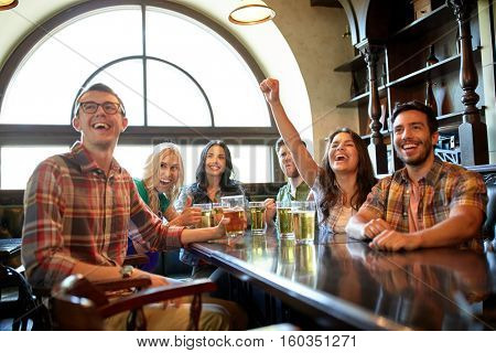 people, leisure, friendship and entertainment concept - happy friends drinking beer, watching sport game or football match and celebrating victory at bar or pub