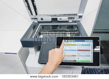 woman press forefinger on the printer touch screen to print documents