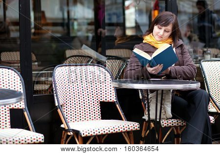 Beautiful Young Girl Reading A Book In Parisian Street Cafe