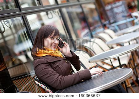 Happy Young Girl Takling On Cell Phone In Parisian Street Cafe