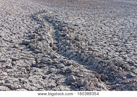 Furrow in dried cracked soil bottom of a dried-up lake