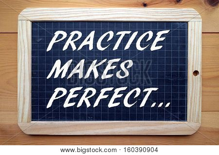 The words Practice Makes Perfect written in white text on a blackboard as a reminder