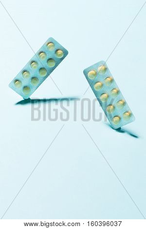 Yellow oral contraceptive pill strips on blue background with shadow.