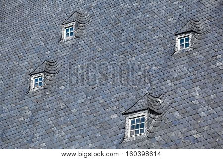 Detail of large gray slate roof and four small nice attic muntin windows (copy space)