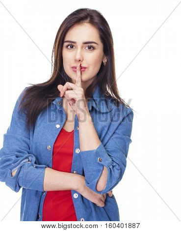 Woman requires silence. Young beautiful brunette girl has put forefinger to lips as sign of silence, isolated on white background