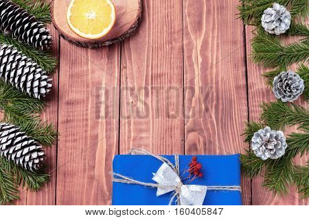 Christmas New Year composition with tangerines, cones, nuts, wicker basket and fir branches in rustic style on old wooden background, selective focus, Background new year, fir, gift, cones, orange, blue ball, red background