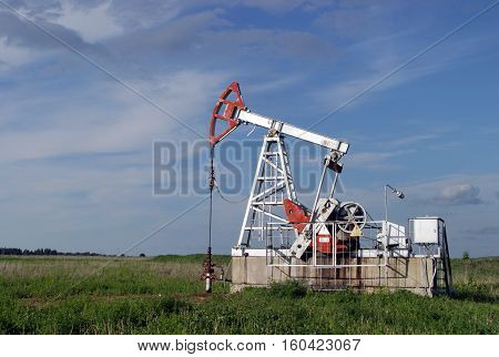 Oil pump in the field on a background cloudy sky in summer