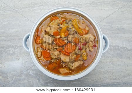 Meat with vegetables in the vase on the gray background