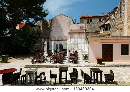 Porec, Croatia - July, 2016 - Empty tables of European cafe on a street in the historic center of Porec, Croatia.